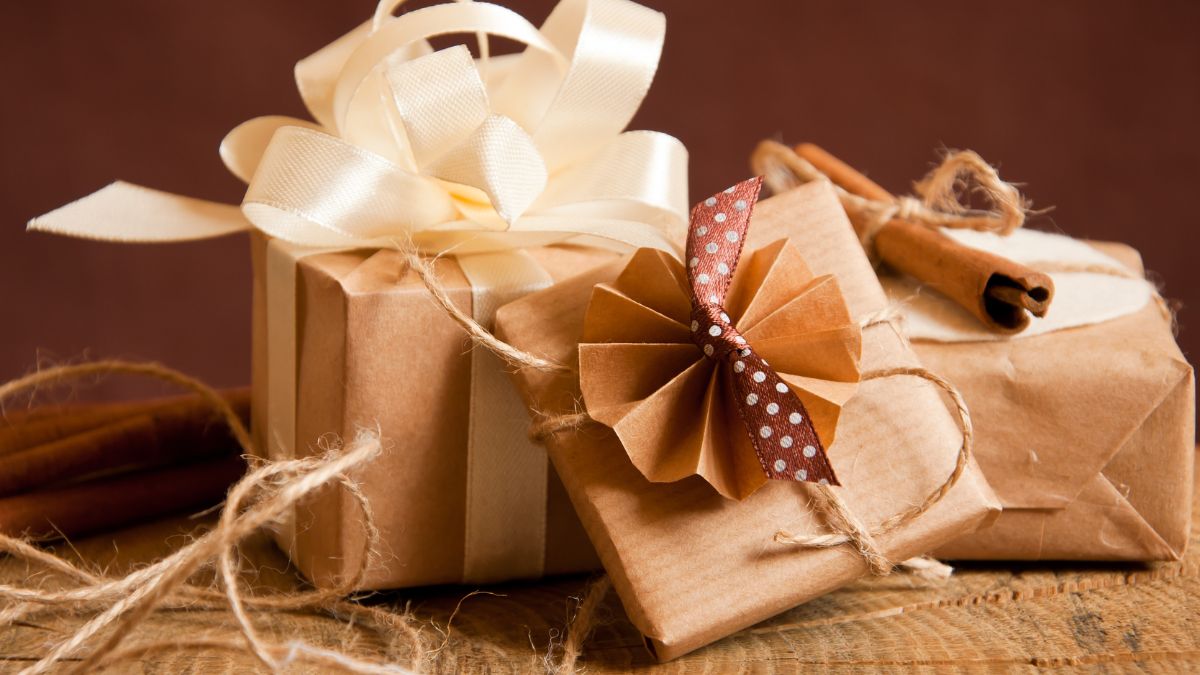 Kreatívan csomagolt ajándékok barna papírból, masnival díszítve.